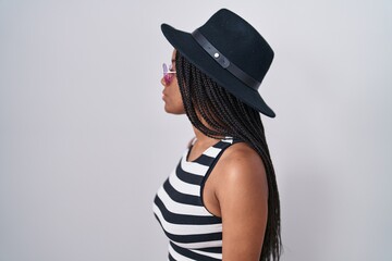 Young african american with braids wearing hat and sunglasses looking to side, relax profile pose with natural face and confident smile.