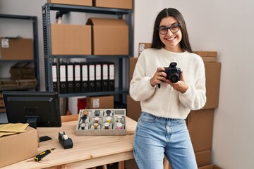 Young hispanic woman ecommerce business worker make photo using professional camera at office