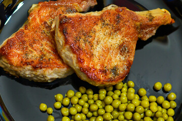 Steak on the bone from pork with green peas in a plate