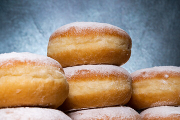 Polish pączki deep-fried doughnuts. Celebrating Fat Thursday (Tłusty czwartek) feast, traditional day in Poland. Pączek food, powdered sugar topped and filled with rose hip jam.