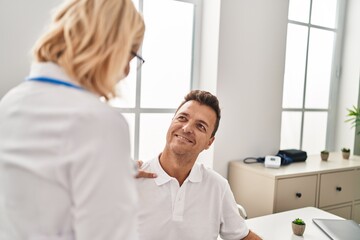 Obraz premium Middle age man and woman doctor and patient having medical consultation at clinic