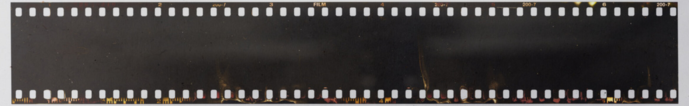 Real Macro Photo Of Long 35mm Filmstrip Under Dirty Glass Plate On White Paper Background. Film Material With Dust. Blank Photo Mock Up.