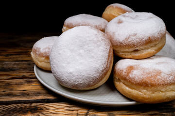 Polish pączki deep-fried doughnuts. Celebrating Fat Thursday, Tłusty czwartek feast, traditional day in Poland. Pączek food, powdered sugar topped and filled with rose hip jam.