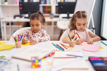 Fototapeta premium Two kids preschool students sitting on table drawing on paper at classroom