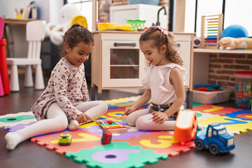 Two kids playing xylophone sitting on floor at kindergarten