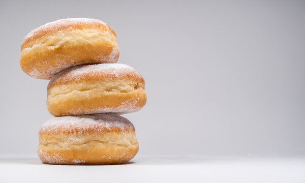 Polish pączki deep-fried doughnuts with copy space. Celebrating Fat Thursday (Tłusty czwartek) feast, traditional day in Poland. Pączek food, powdered sugar topped and filled with rose hip jam.