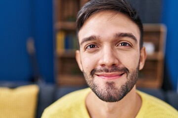 Young hispanic man smiling confident sitting on sofa at home