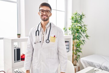 Hispanic man wearing doctor uniform and stethoscope with a happy and cool smile on face. lucky...