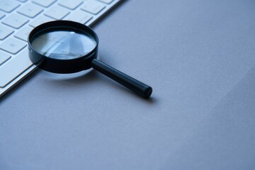 Magnifying glass and laptop keyboard. Seo.