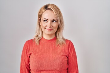 Obraz premium Blonde woman standing over isolated background smiling looking to the side and staring away thinking.