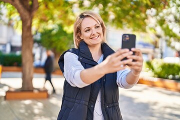 Young blonde woman smiling confident making selfie by the smartphone at park