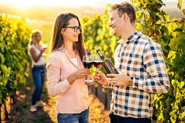 Cheerful millennial caucasian couple tasting wine together on a wineyard - Harvesting, wine tasting and vinification outdoor concept with 20s people on a rural vine farm in sunset