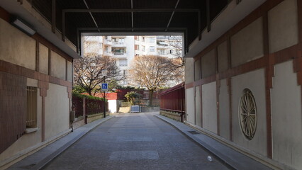 Passage en tunnel ou entre historiques, vieilles colonnes de pierre, accès à une résidence de logements et d'immeubles, à l'ombre et mal éclairée par le soleil, vide et personne