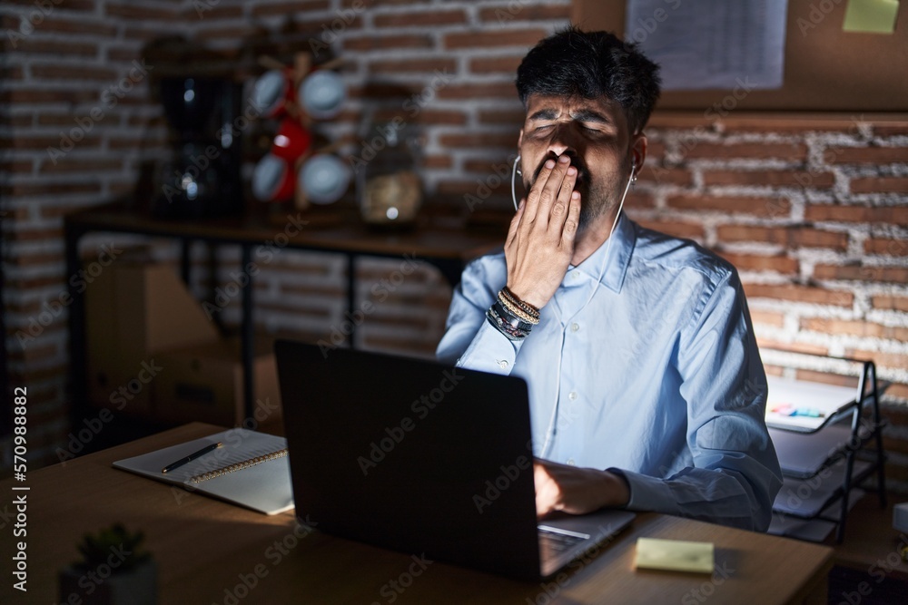 Sticker Young hispanic man with beard working at the office at night bored yawning tired covering mouth with hand. restless and sleepiness.