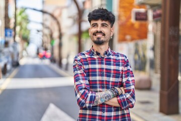 Fototapeta premium Young hispanic man smiling confident standing with arms crossed gesture at street