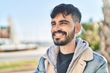 Young hispanic man smiling confident looking to the side at street