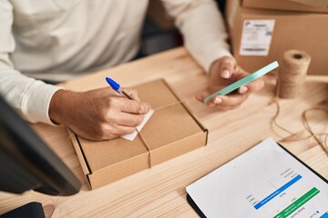 Middle age man ecommerce business worker using smartphone writing on package at office