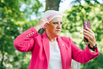 senior woman dressed in pink puts pink scarf on her head