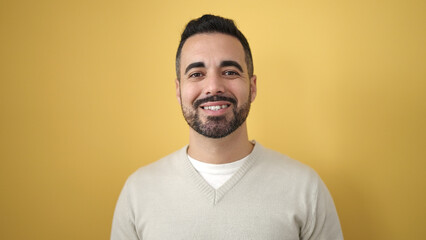 Young hispanic man smiling confident standing over isolated yellow background