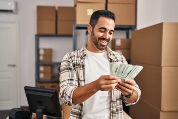Young hispanic man ecommerce business worker counting dollars at office