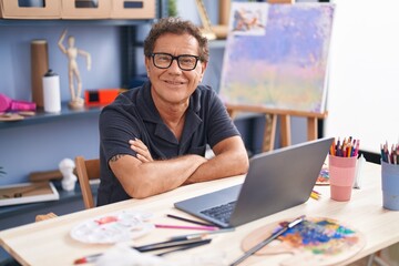Fototapeta premium Middle age man artist smiling confident using laptop at art studio