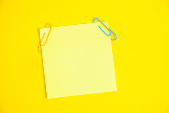 Yellow sticker for notes and paper clips yellow background.