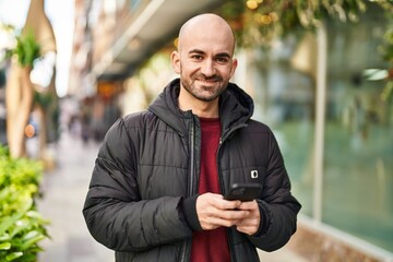 Naklejka premium Young man smiling confident using smartphone at street