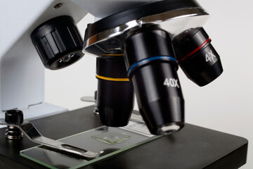 The child looks into the eyepiece of a microscope on a white background. Close-up, selective focus.