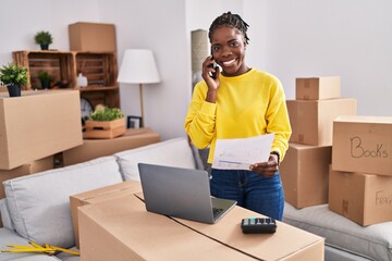 African american woman talking on the smartphone standing at new home