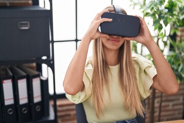 Young beautiful hispanic woman business worker using virtual reality glasses at office