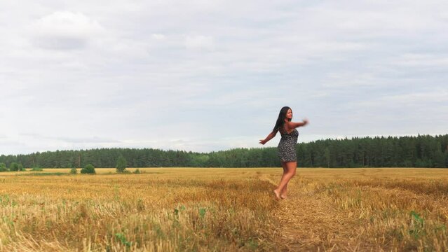 Young woman dance on a wheat field with sunrise on the background