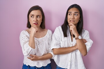 Hispanic mother and daughter together thinking worried about a question, concerned and nervous with hand on chin