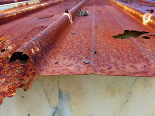 Rusty and holed sheet metal background. Metallic corrugated sheet roof texture. Deep broken profiled sheet panel. Corrugated Metal Roof Exterior Close up.