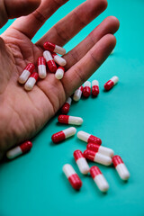 Close-up of pills held by a man's hand against a green background.