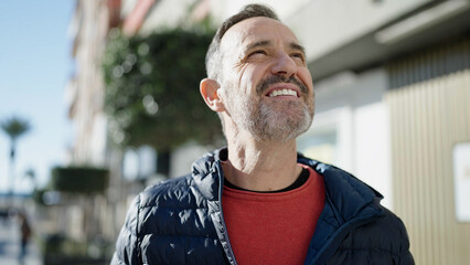 Middle age man smiling confident looking to the sky at street