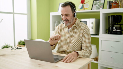 Middle age man having video call sitting on table at home