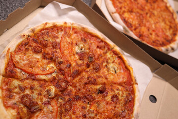 Whole pizzas with cheese, ham and tomatoes in a delivery box