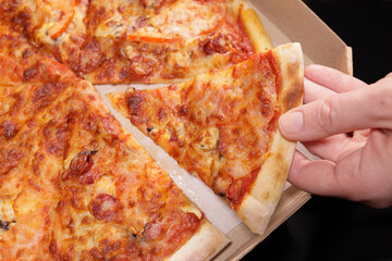 Male hand takes a piece of pizza