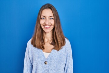 Fototapeta premium Young woman standing over blue background with a happy and cool smile on face. lucky person.