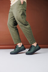 Summer shoes. Close-up of male legs in green pants and green casual sneakers. Summer leather men's shoes