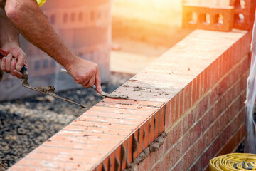 Close up of a brick wall and jointer trowel used by the worker to apply and level the mortar between bricks. Bricklayer making finishing touches to the brick wall and filling joints with mortar