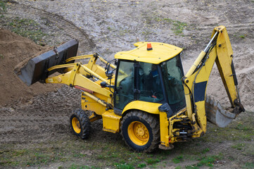 Yellow tractor-based bulldozer excavator at a construction site.Earthmoving machine. Leveling the soil for the construction of a new house. 