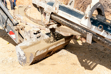 Concrete mixer truck pouring fresh wet concrete into excavators bucket at a construction site