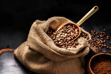 Scoop of coffee beans in a bag on dark board. Ground coffee in a cup and instant coffee in a wooden cup. Place for text.