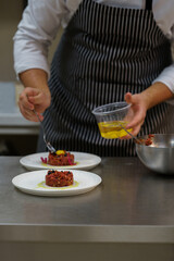 The cook decorates the meat dish.