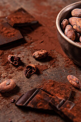 Tasy cocoa powder, beans and dark chocolate in a wooden background