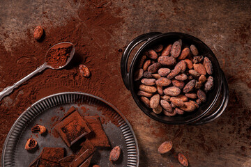 Tasy cocoa powder, beans and dark chocolate in a wooden background