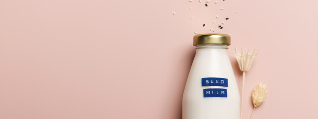 sesame seed milk in bottle on beige background with plant.copy space. Raw diet meal. Healthy...
