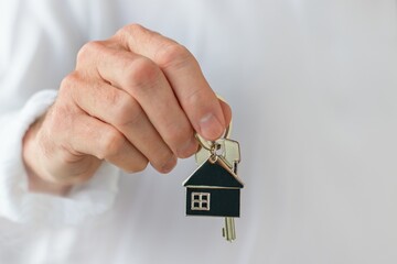 Man's hand holding a house key. Concept of buying a new house or home.