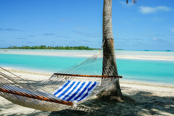 Hammock slung between palms in shade by waters edge of tropical holiday destination